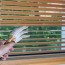 a woman s hand cleans wooden blinds